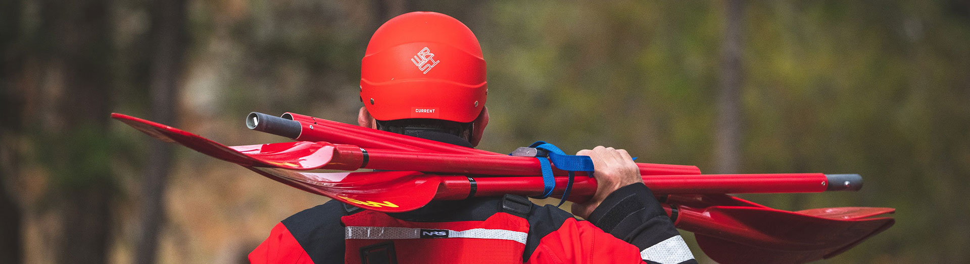 Fire fighter in red water gear with oars over his shoulder