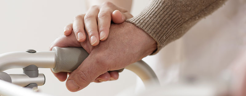 elderly couple hold hands on walker