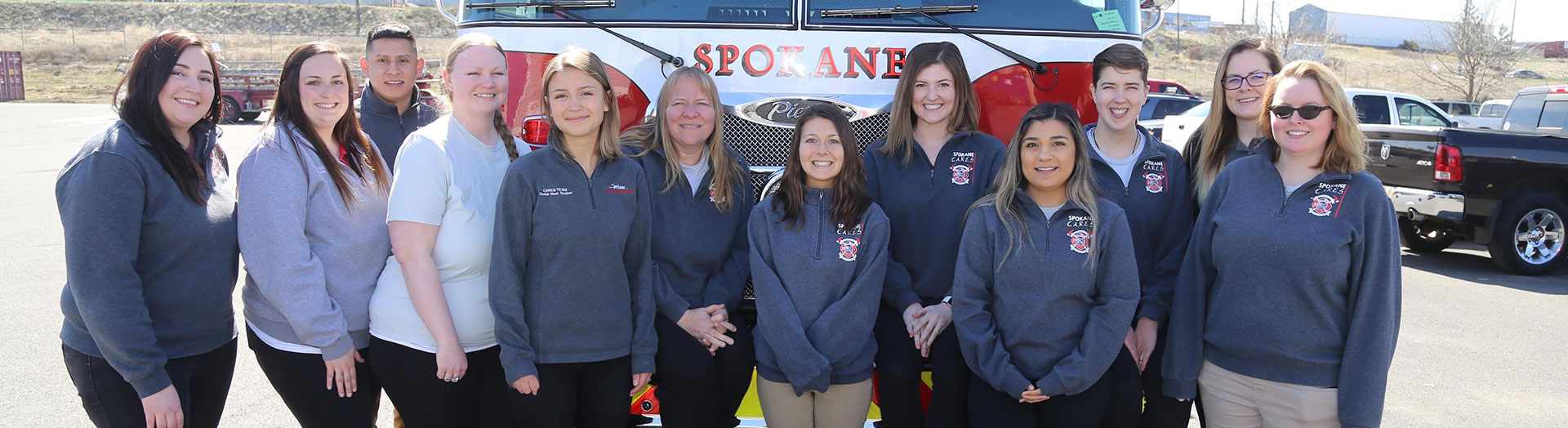 a group of female fire fighters pose in front of a fire truck.